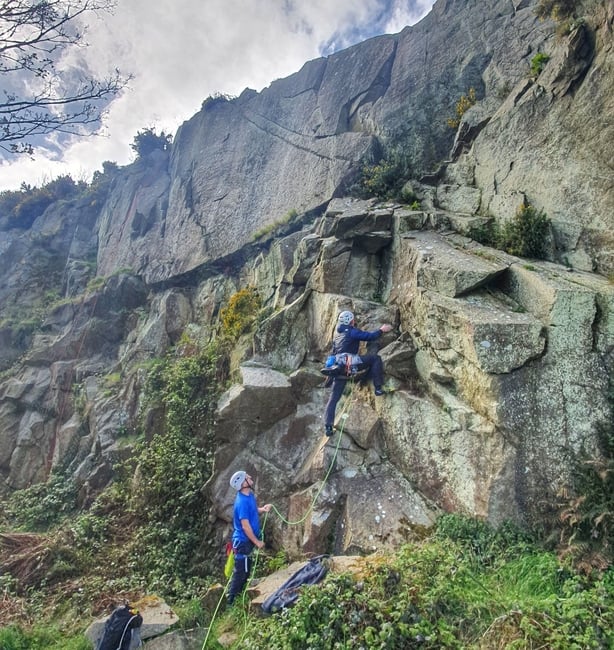 People climbing up a wall in Dalkey Quarry