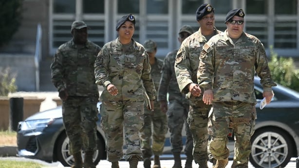 A number of people wearing military uniform walk on the street in Washington DC
