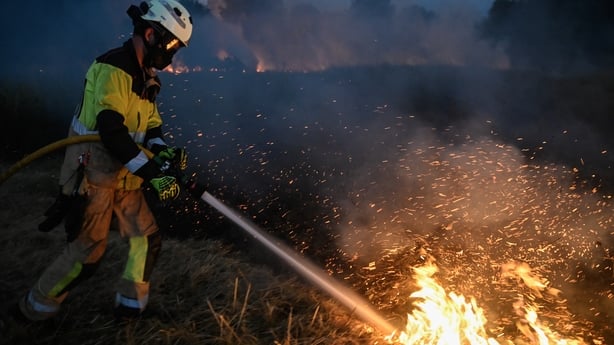 a firefighter sprays water over flames 
