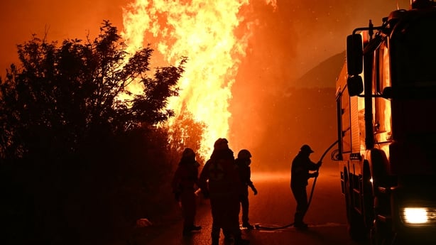 Firefighters work to extinguish a wildfire near the city of Patras in western Greece