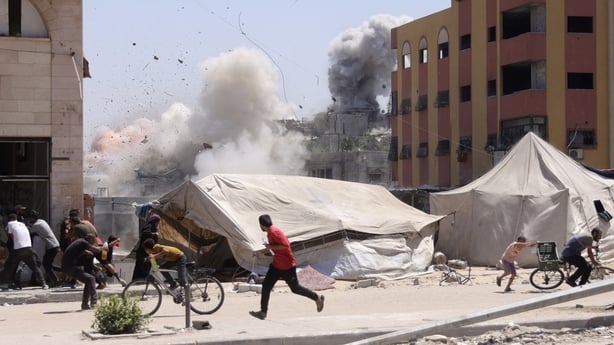 Palestinians rush for cover as smoke billows after an Israeli strike on a building in Jabalia in northern Gaza