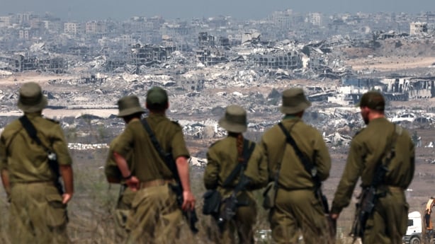 Israeli army soldiers look at destroyed buildings in Gaza