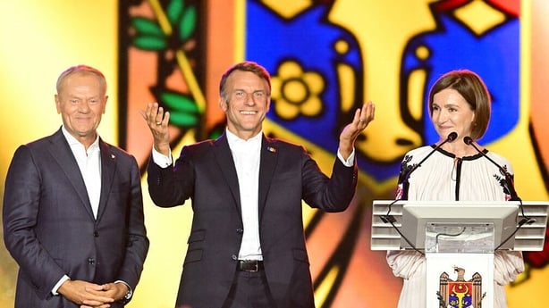 French President Emmanuel Macron gestures as he stands next to Polish Prime Minister Donald Tusk and Moldova's President Maia Sandu