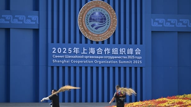 People walk in front of a sign 