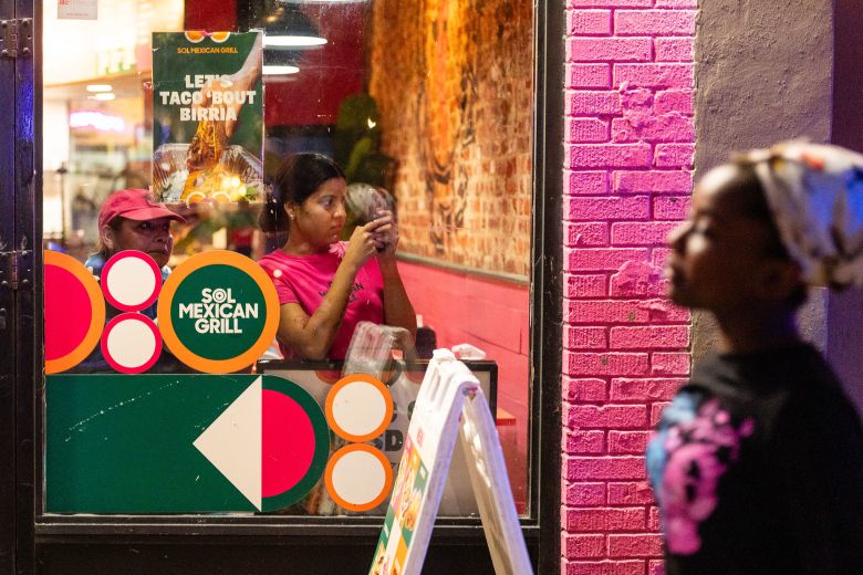 Workers at a Sol Mexican Grill watch and film as Metropolitan Police Department officers detain a man on Wednesday.