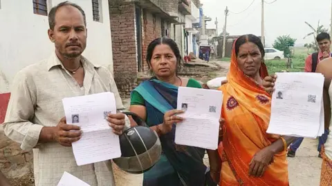 Hindustan Times via Getty Images Villagers showing forms during door to door distribution of Enumeration Forms at rural area on July 4, 2025 in Patna, India. 