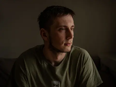 BBC Pavlo, dark-haired and dressed in a green T-shirt, looks away from the camera