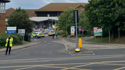 Maddie Murphy A number of police cars outside QEQM hospital in Margate , with several officers in hi-vis and blue and white incident tape across the entrance to the car park.