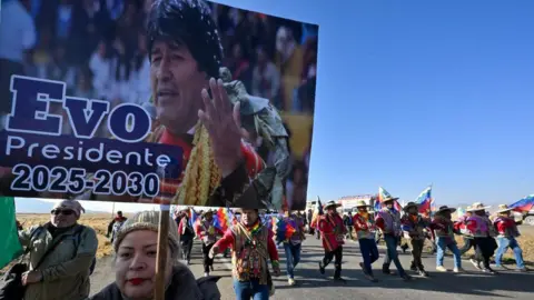 AFP via Getty Images Supporters holding a banner of Bolivian former President Evo Morales in a march.