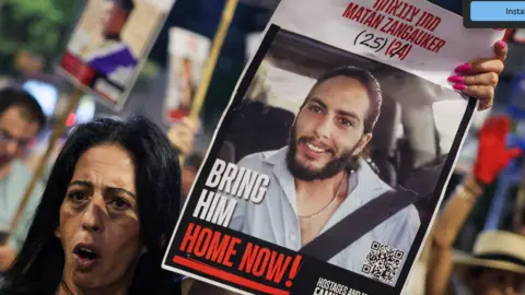 JACK GUEZ/AFP via Getty Images Enav Zangauker holds a portrait of her kidnapped son, Matan, during an anti-government protest calling for action to secure the release of Israeli hostages held captive in Gaza.