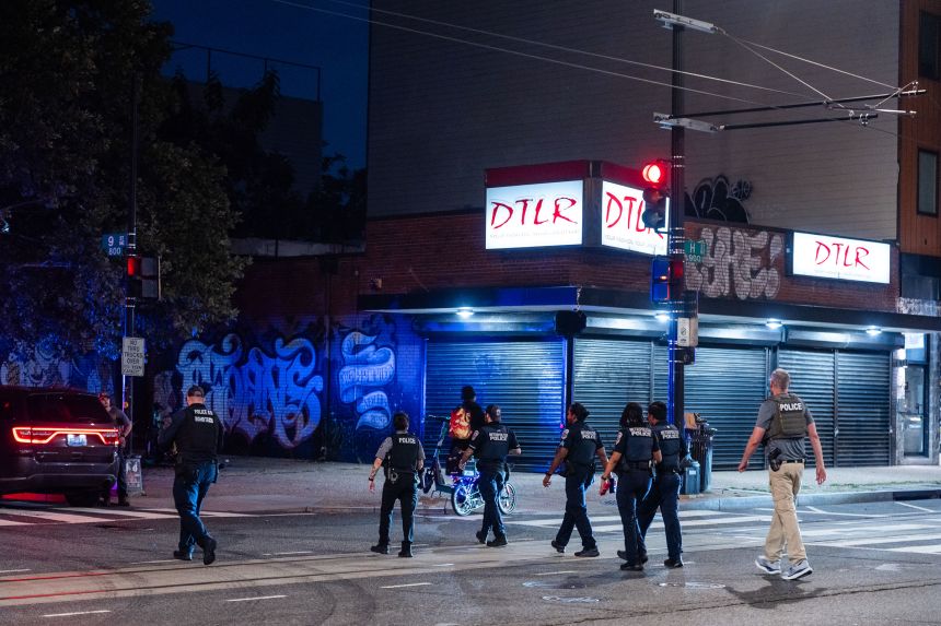 Metropolitan Police Department officers, MetroTransit Police Department officers and a federal officer leave an apartment building after responding to a call on H Street corridor in Washington, DC, on Wednesday.