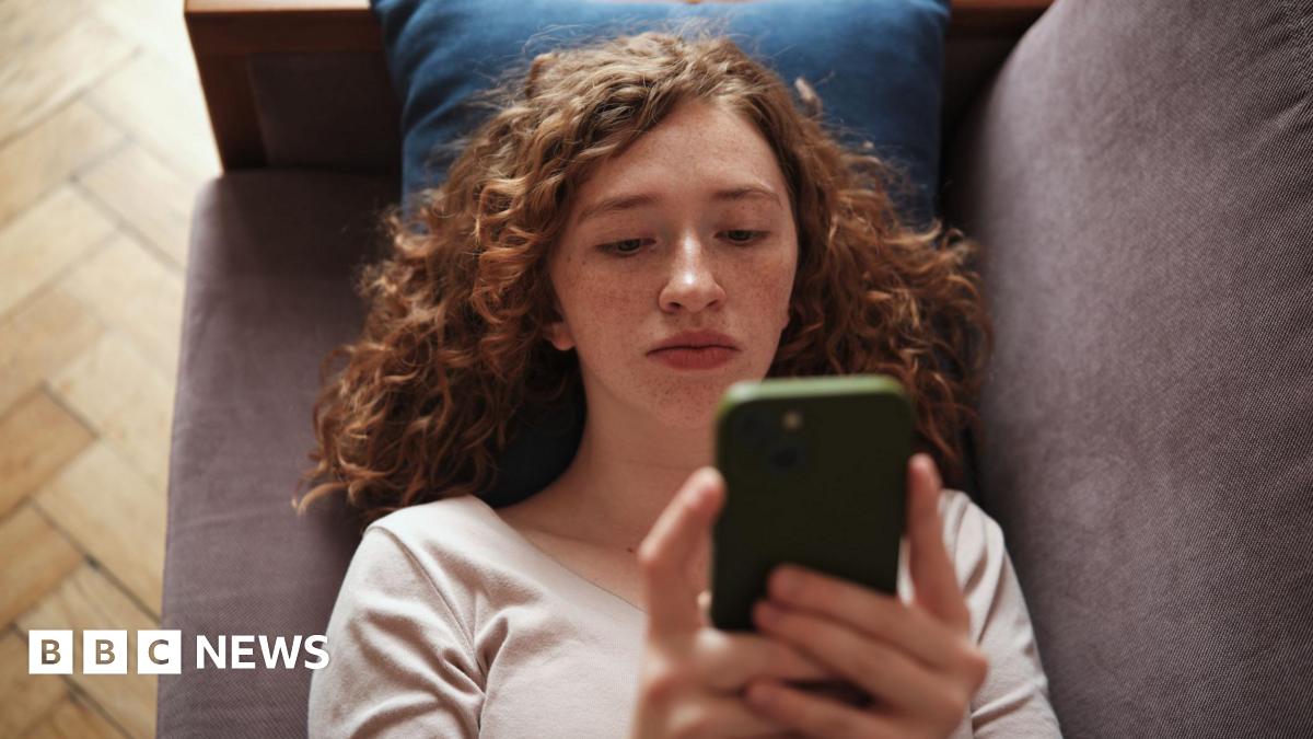 Sarah Ezekiel smiling. She is a woman with greying, curly, shoulder-length hair. She is wearing black-rimmed glasses.