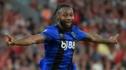 Reuters Semenyo celebrating after scoring for Bournemouth. He had short dreadlocked hair and a dark brown beard. He was wearing his dark blue and black Bournemouth away kit.