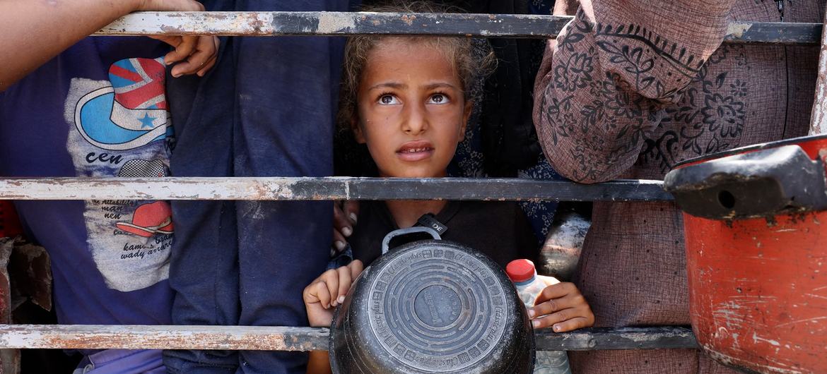 A young girl from Gaza waiting to fill her container with lentils.