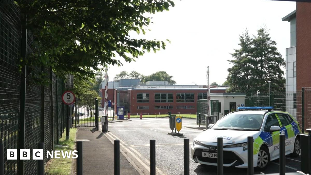 A police car is behind black bollards close to the car park where a 19-year-old was killed.