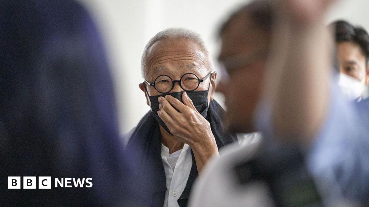 Ong Beng Seng wearing a black mask and round spectacles. He is covering his mouth with his hand.