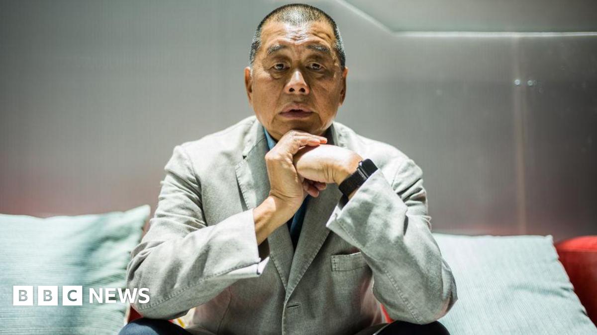 Jimmy Lai, in a gray suit and black pants, poses for a photograph during an interview with AFP news agency in Hong Kong