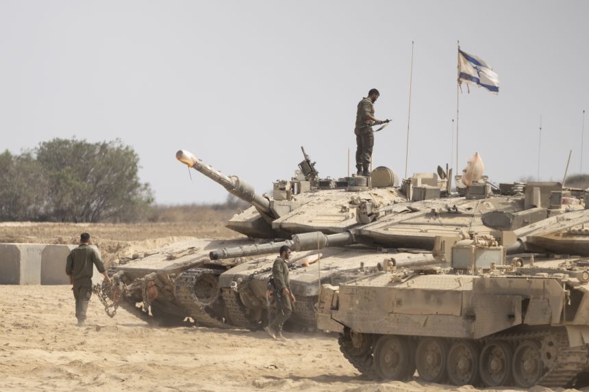Israeli soldiers work near tanks in a gathering point near the border with the Gaza Strip, in Southern Israel, Israel on Wednesday.