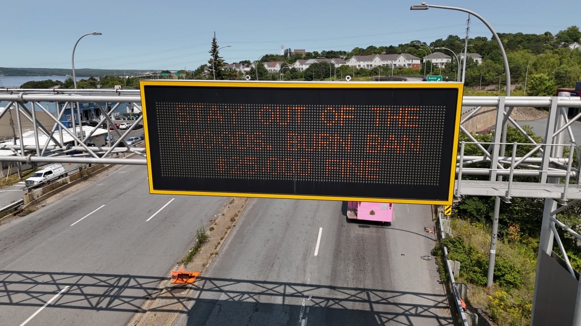 A sign over a Nova Scotia road saying "Stay out of the woods, burn ban, $25,000 fine."
