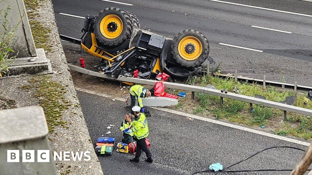 Tractor falls off bridge onto M20 leaving man in hospital