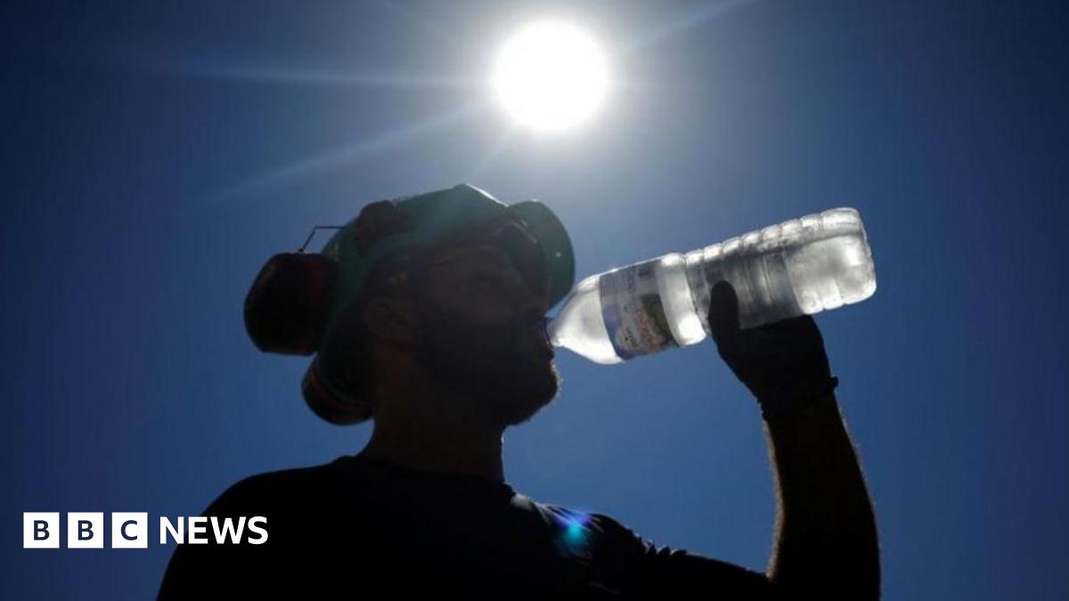Labourers wearing hi-viz orange tops drink water to cool down as they work on a construction site of tramway lines along the Garonne river in France