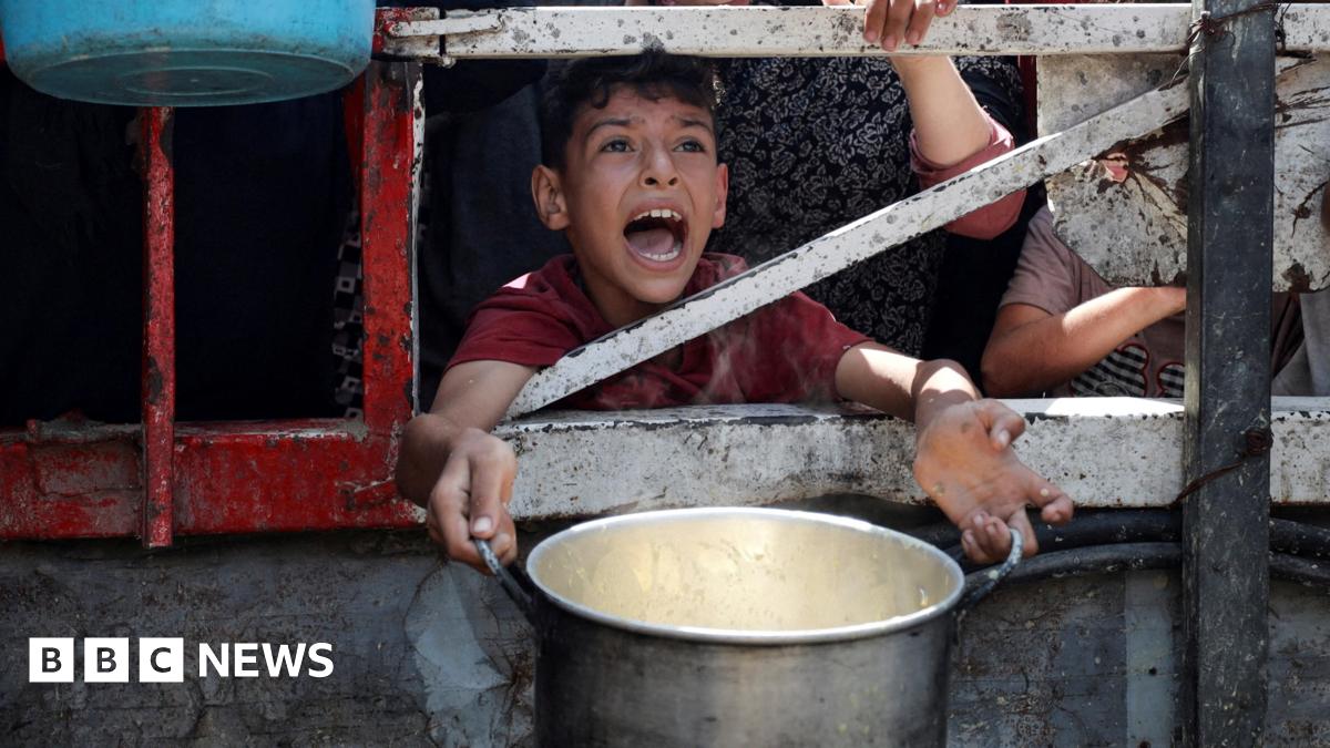 A Palestinian child is caught mid shout, eyes full of anguish, as he waits to receive food from a charity kitchen, amid a hunger crisis in Gaza