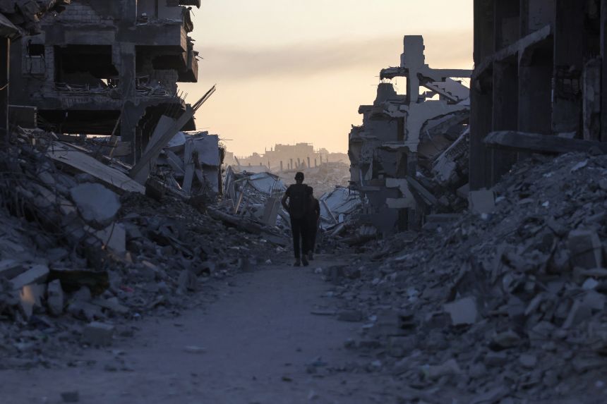 Men walk between piles of rubble in Saftawi neighbourhood, west of Jabalia in the northern Gaza Strip, on August 24, 2025, amid the ongoing war between Israel and the Palestinian Hamas militant group.