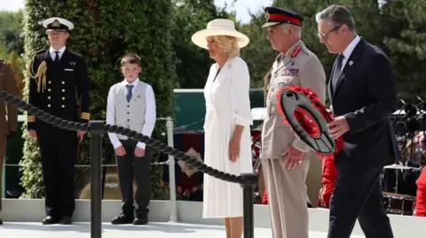 PA Media King Charles III (second from right) and Queen Camilla (third from right) stand as Prime Minister Sir Keir Starmer lays a wreath during the national Service of Remembrance to mark the 80th Anniversary of VJ Day at the National Memorial Arboretum in Alrewas, Staffordshire
