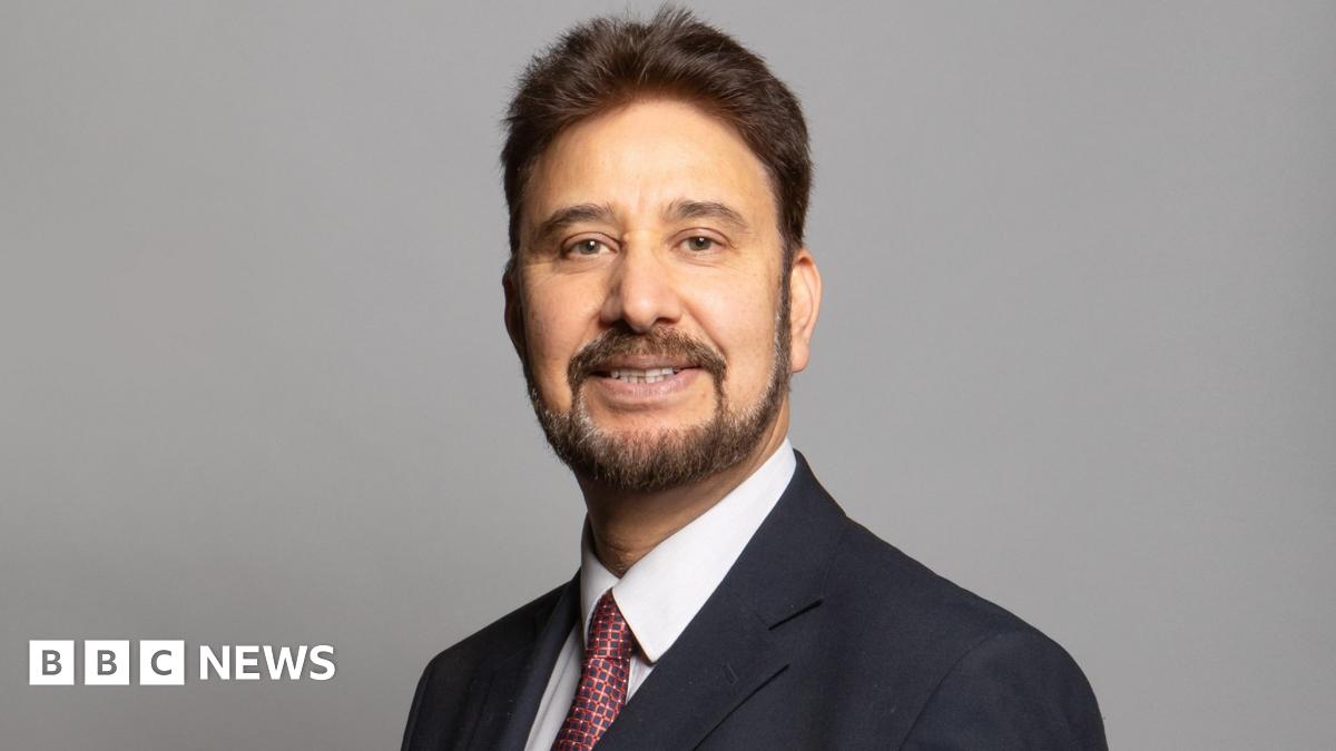 Official portrait of Afzal Khan, a middle aged man wearing a blazer and checked red tie