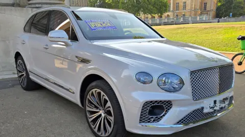 Met Police A white Bentley with a sign that reads: "Seized by Police" on the bonnet.