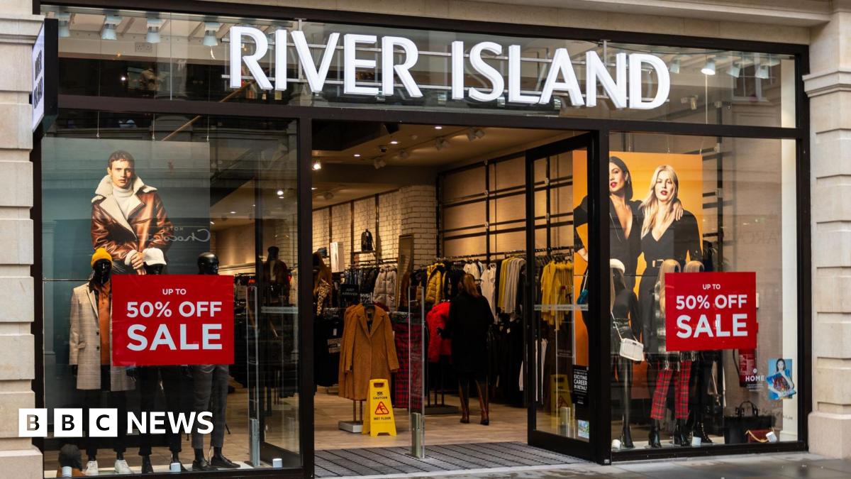 A River Island shop front, with red "50% off sale" signs in the windows.