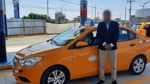 Submitted photo A man in a suit stands in front of a cab, his face blurred, outside a gas station