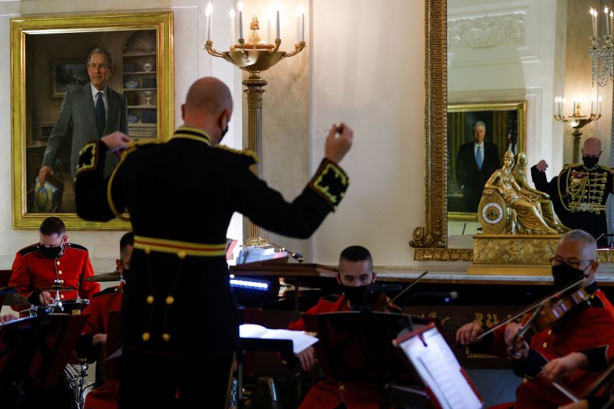 Former President George W. Bush's White House portrait is seen at left, as members of the US Marine Band play holiday music during a press tour of White House Christmas decorations in November 2021.