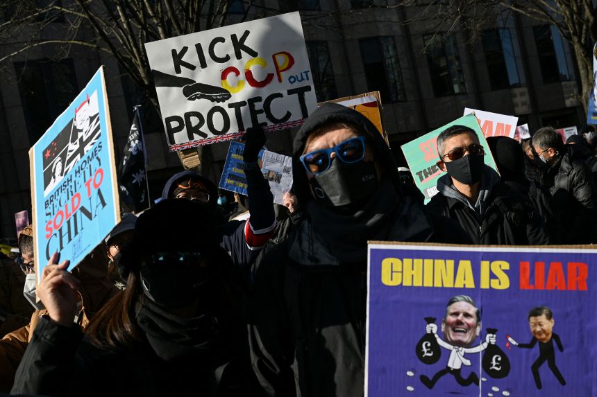 Protesters hold placards during a demonstration outside Royal Mint Court against the proposed site of the new Chinese embassy.
