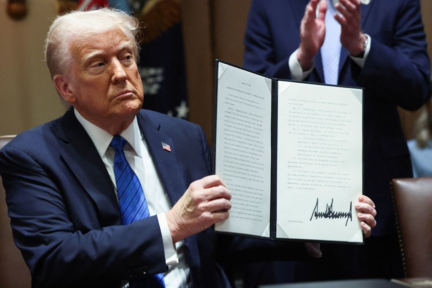 President Donald Trump holds an executive order, at the White House, in Washington, DC, on March 25.
