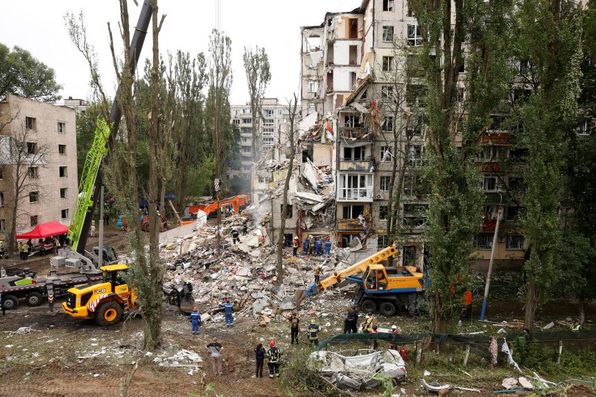 Emergency personnel work at the site of a partially collapsed apartment building hit in a Russian strike on Kyiv overnight into Thursday.
