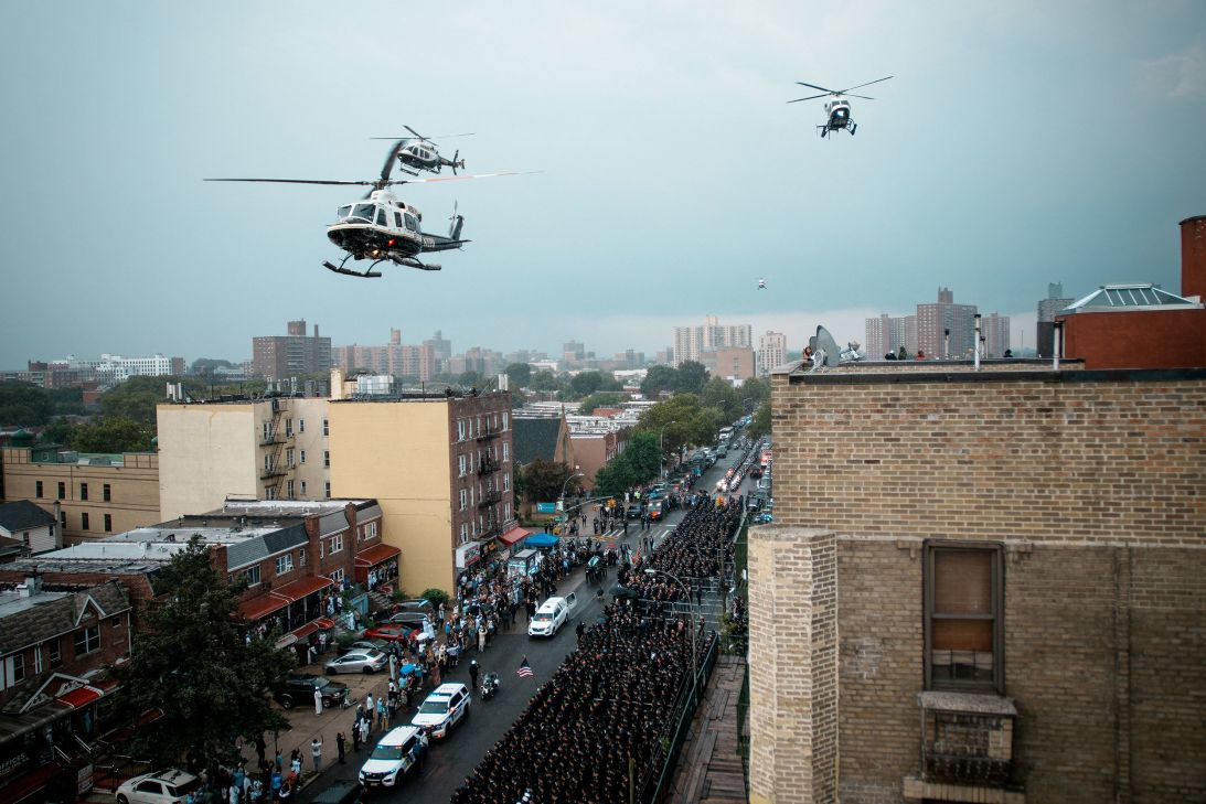 Helicopters fly overhead as Islam's coffin is driven past a wall of loved ones, mourners and law enforcement officers.
