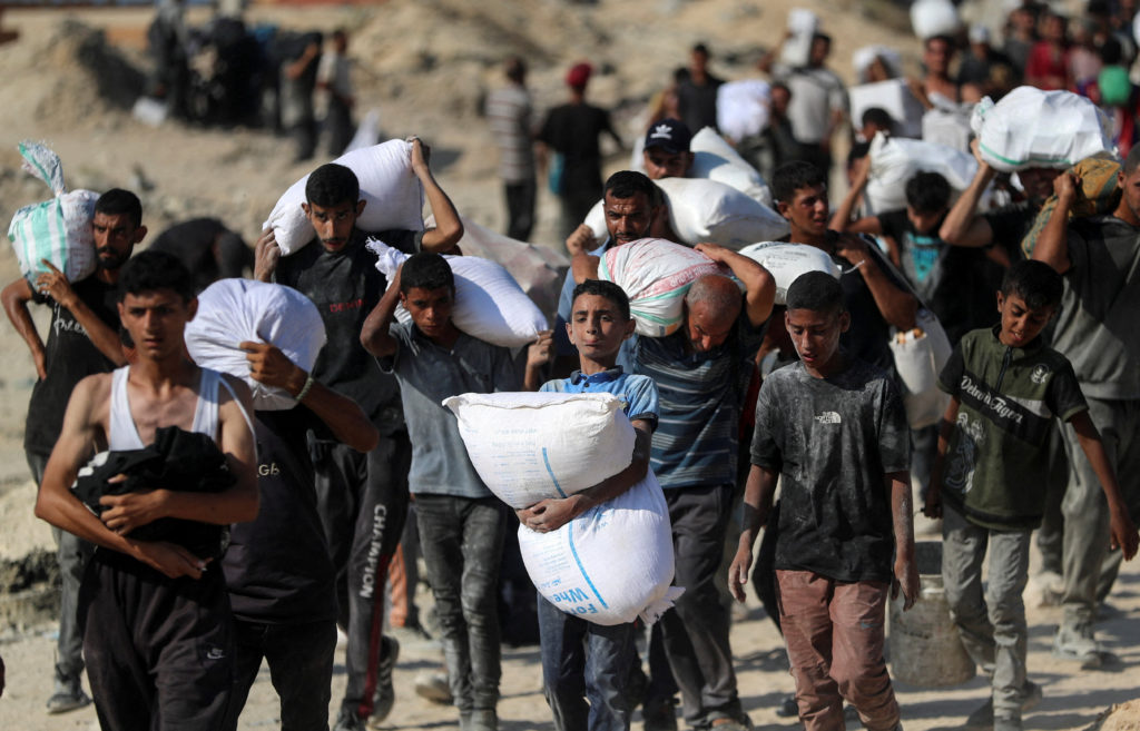 Palestinians carry aid supplies that entered Gaza through Israel, in Beit Lahia