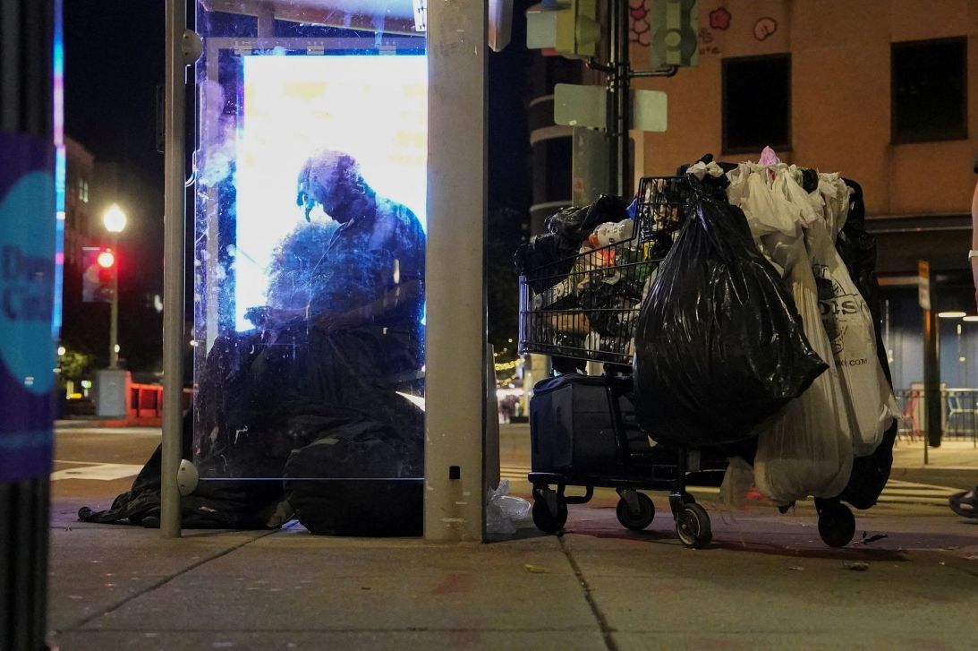 A homeless person sits at a bustop in Washington, DC's Dupont Circle, on Monday.