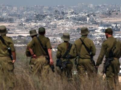 Israeli soldiers look at destroyed buildings in the Gaza Strip as they stand on the border with the Palestinian territory, on August 13, 2025.