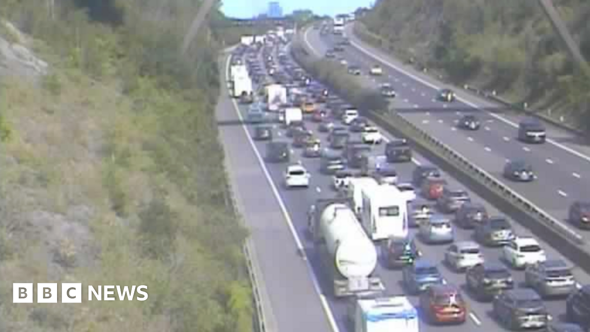 A traffic camera image of the motorway, which shows extremely heavy traffic across four lanes. Cars, caravans and lorries can be seen queuing on the road.