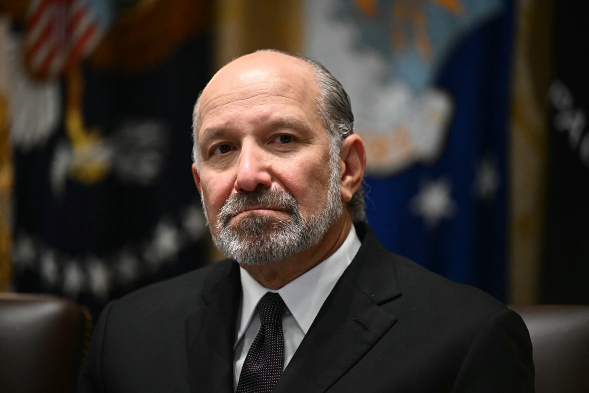 A balding bearded man in a suit and tie is shown in closeup.