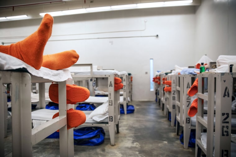 A detainee lays on a bunk in a pod