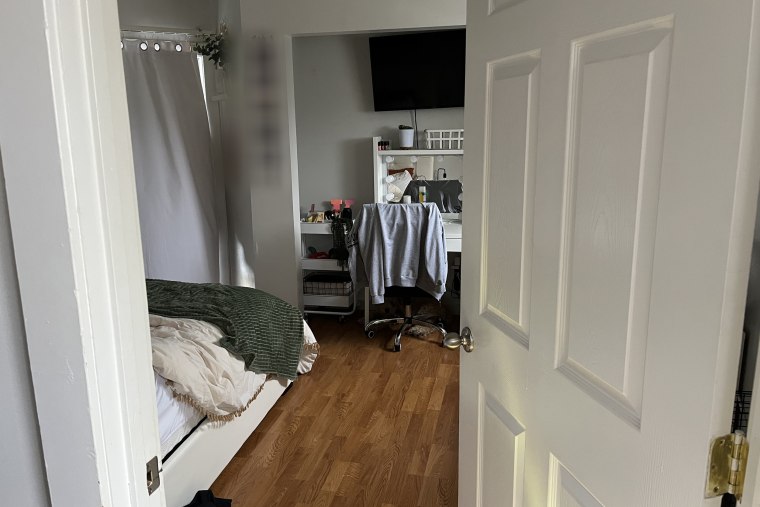 Leading into empty room, bed on left, blurred photos on wall but no sign of blood, etc.