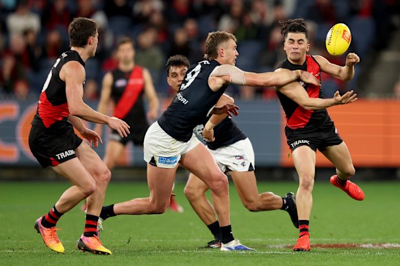 Isaac Kako of the Bombers handballs whilst being tackled by Patrick Cripps of the Blues.