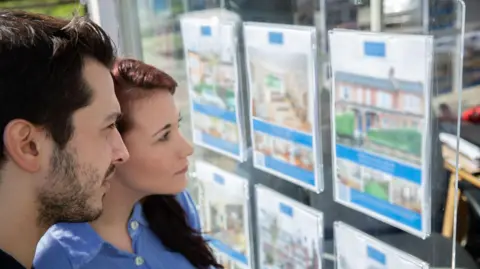 Getty Images Homebuyers look at an estate agents window display - stock shot