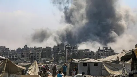 EPA Palestinians flee as smoke is seen billowing over Gaza City following an Israeli air strike. Photo: 30 August 2025