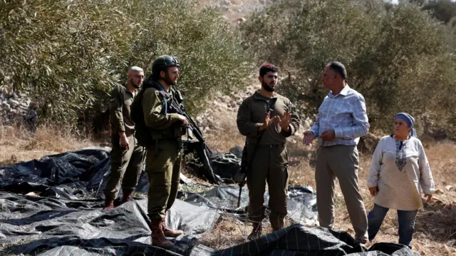 Israeli soldiers wit two elderly Palestinian farmers for olive fields near Nablus, for di Israeli-occupied West Bank.