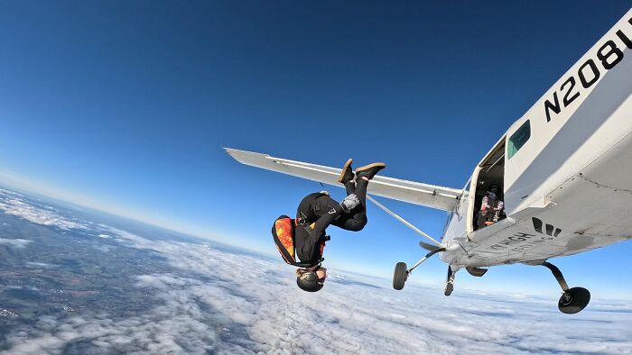 Woman in skydiving gear performing a 15,500-ft jump from a small airplane above the clouds after breakup choice