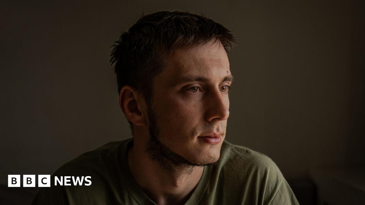 Pavlo, dark-haired and dressed in a green T-shirt, looks away from the camera